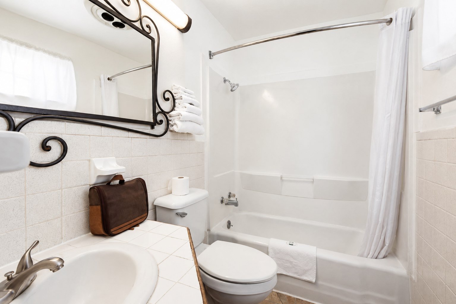 Bright bathroom with a tub and shower at Capri Motel